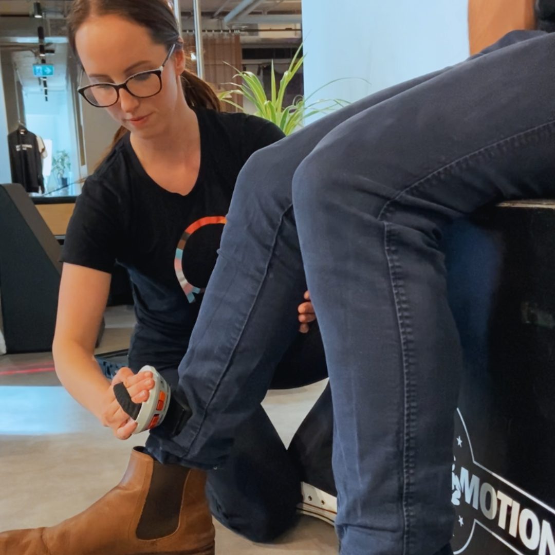 Physiotherapist using a hand-held dynamometer to measure leg strength.